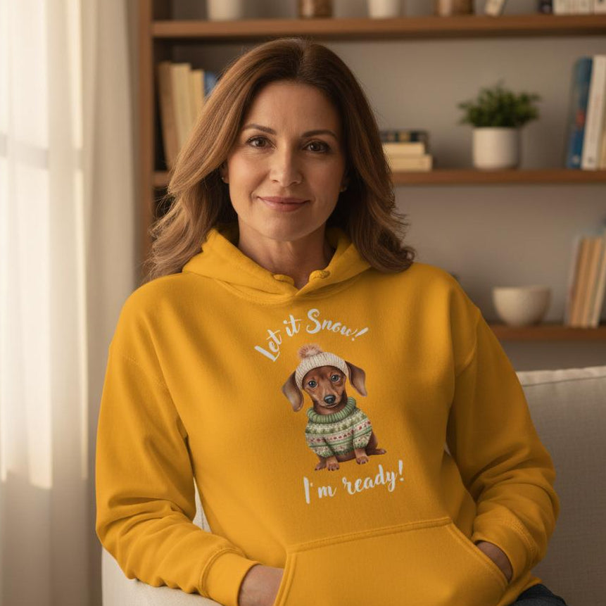 Woman wearing a yellow hoodie with a dog graphic and text, sitting on a couch in a cozy room.