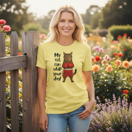 Woman wearing a yellow t-shirt with a graphic of a cat in boxing gloves and text, standing in a garden.